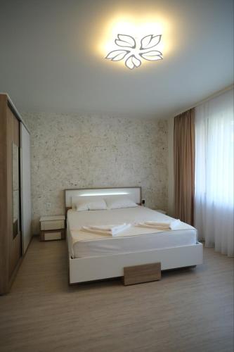 a bedroom with a white bed with a light above it at Апартамент за гости Симона in Smolyan
