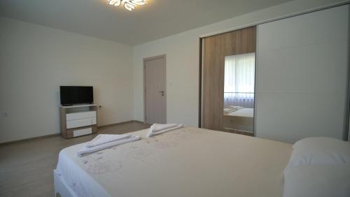 a white bedroom with a bed and a television at Апартамент за гости Симона in Smolyan