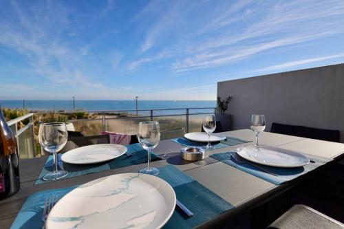 une table avec des assiettes et des verres à vin sur un balcon dans l'établissement NAUTILIA 204 - Supérieure Luxe - 2 personnes, au Cap d'Agde