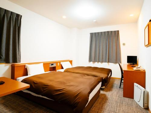 a hotel room with two beds and a desk at Kumamoto Ichibamae Business Kurenai Hotel in Kumamoto