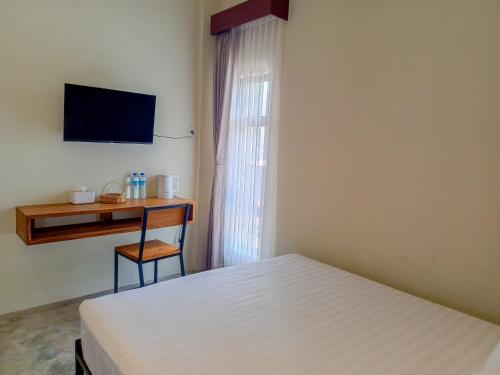 a bedroom with a bed and a desk and a television at BRICK HOUSE - Unique & Central in Selaparang