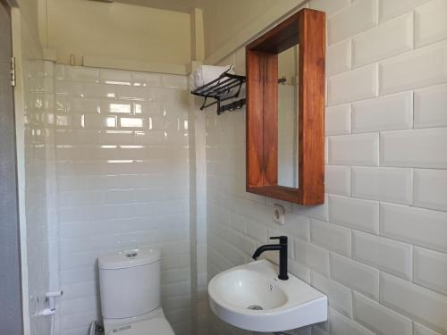 a bathroom with a toilet and a sink and a mirror at BRICK HOUSE - Unique & Central in Selaparang