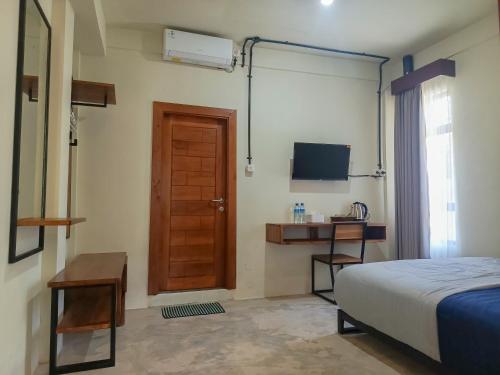 a bedroom with a bed and a desk and a door at BRICK HOUSE - Unique & Central in Selaparang