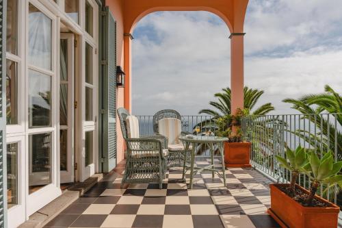 a patio with chairs and a table on a balcony at Reid's Palace, A Belmond Hotel, Madeira in Funchal