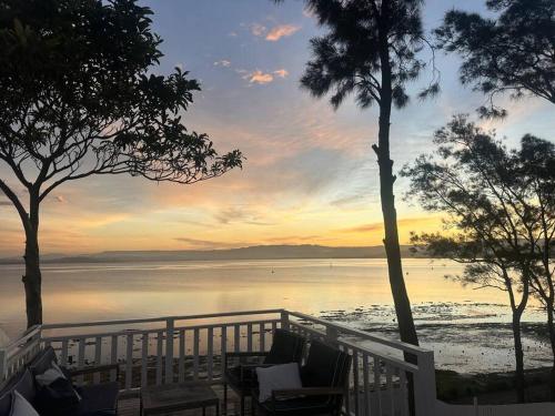 a sunset over the water with chairs and trees at Dreamy Lake Retreat & Sunsets in Lake Heights