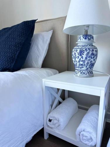 a blue and white lamp on a white table next to a bed at Dreamy Lake Retreat & Sunsets in Lake Heights