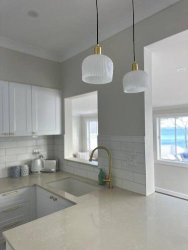 a white kitchen with a sink and two pendant lights at Dreamy Lake Retreat & Sunsets in Lake Heights