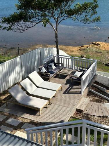 a wooden deck with lounge chairs and a tree at Dreamy Lake Retreat & Sunsets in Lake Heights