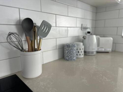 a kitchen counter with utensils in a container on a counter at Dreamy Lake Retreat & Sunsets in Lake Heights