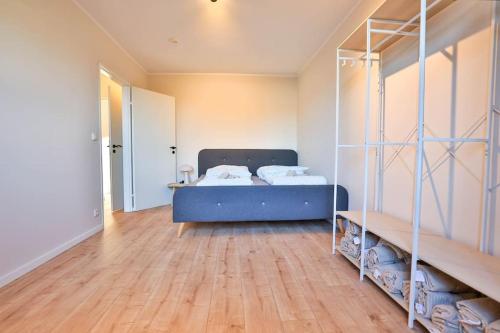a bedroom with a blue bed and a wooden floor at Meersinn Ferienwohnung Brake in Harrierwurp