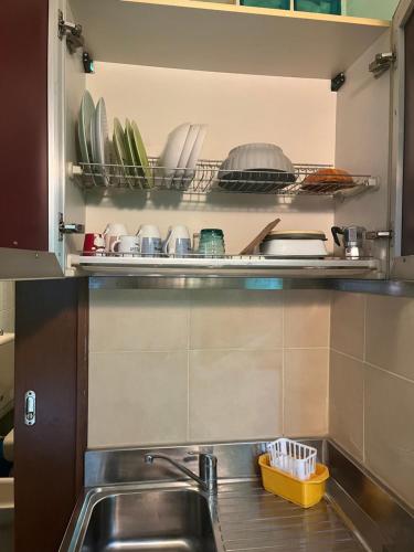 a kitchen with a sink and a shelf with dishes at Agrihome Di Alberto Giuseppe Gulotta B&B Bella Vista Appartamento Salvia in Massarosa