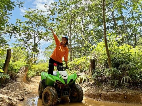a woman riding a four wheeler on a dirt road at Yambaru Experience Hotel Nunganiku in Higashi