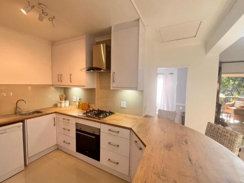 a kitchen with white cabinets and a wooden counter top at Zulu Sunset Luxury Apartment in St Lucia