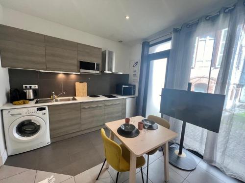 une cuisine avec une table et une machine à laver dans l'établissement Calme & chic - Jean Jaurés - Gare Matabiau, à Toulouse