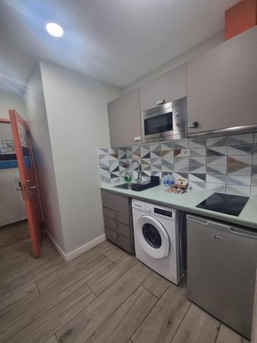 a kitchen with a washing machine and a microwave at Hotel Apartamento Bajamar in Las Palmas de Gran Canaria