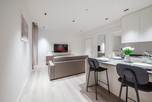 a white kitchen with a counter and stools in a room at Vittoria Apt Luxury e Design in Duomo in Brescia