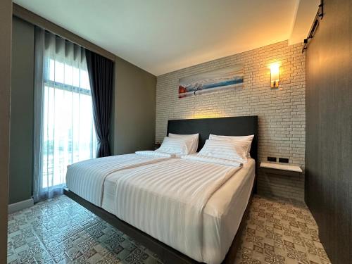 a bedroom with a large white bed with a brick wall at BB HOUSE Rangsit in Ban Talat Rangsit