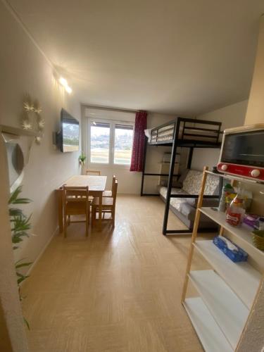 ein kleines Zimmer mit einem Tisch und einem Etagenbett in der Unterkunft Studio au pied des pistes in Le Dévoluy