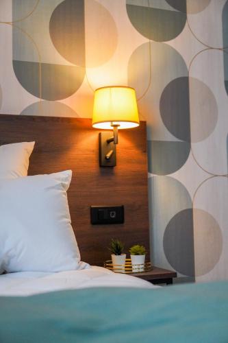a bedroom with a bed and a lamp on a wall at KoonTy - Chambres et Appartements à Landerneau in Landerneau