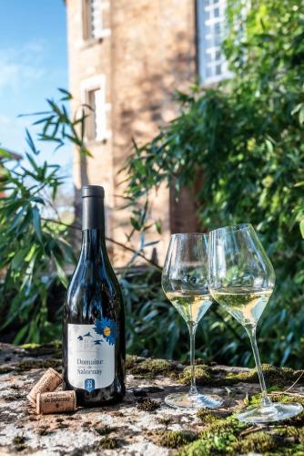 une bouteille de vin et deux verres sur une table dans l'établissement Château de Salornay, à Hurigny