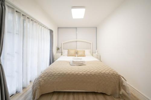 a bed in a white room with a large window at Tonight Homestay South Shanxi Road Shanghai in Shanghai