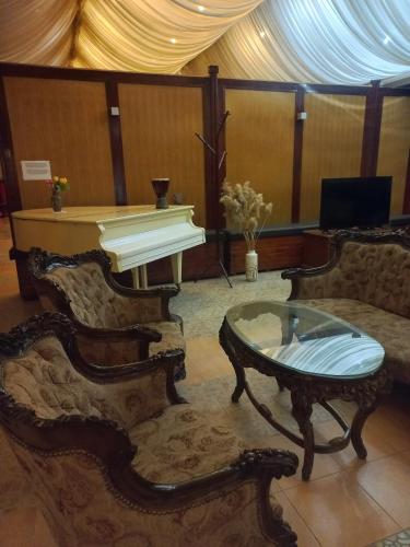a living room with a piano and a coffee table at Hotel Duga in Novi Sad
