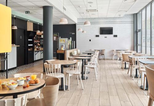 a restaurant with tables and chairs and a tv at B&B HOTEL Champigny-sur-Marne in Champigny-sur-Marne