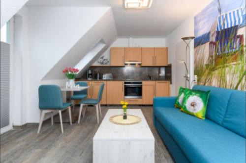 Una sala de estar con un sofá azul y una mesa. en Haus Strandkorb FeWo Strandkob 7, en Bensersiel