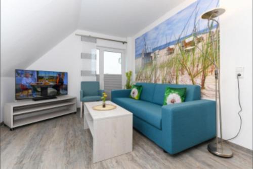 a living room with a blue couch and a tv at Haus Strandkorb FeWo Strandkob 8 in Bensersiel