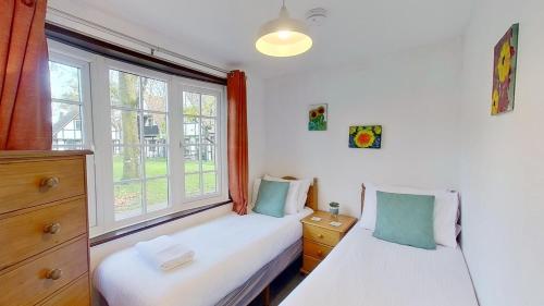 two twin beds in a room with a window at 14 Tudor Court, Tolroy Manor in Hayle