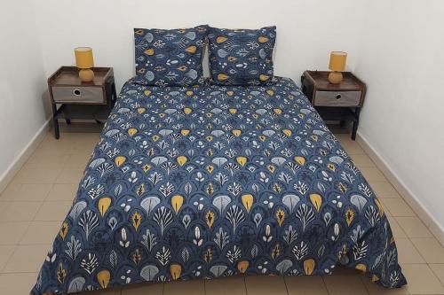 - un lit avec une couette bleue et 2 tables de chevet dans l'établissement Appartement T2 avenue Maréchal juin, à Ajaccio