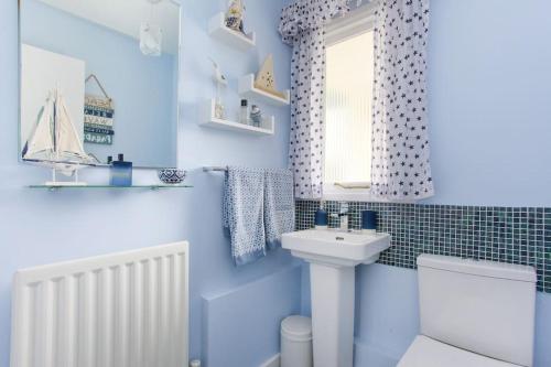 ein blaues Bad mit einem Waschbecken und einem WC in der Unterkunft Wildwoods - just moments from the beach! in Worth