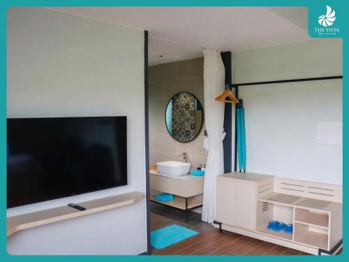 a bathroom with a television and a bathroom with a tub at The Vista Beach Resort Phan Thiết in Phan Thiet