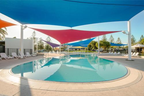 einen Pool mit Sonnenschirmen und Stühlen in einem Resort in der Unterkunft BIG4 West Beach Parks in Adelaide