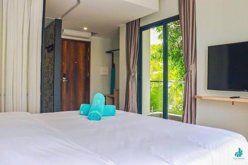 a bedroom with a large white bed with a tv at The Vista Beach Resort Phan Thiết in Phan Thiet