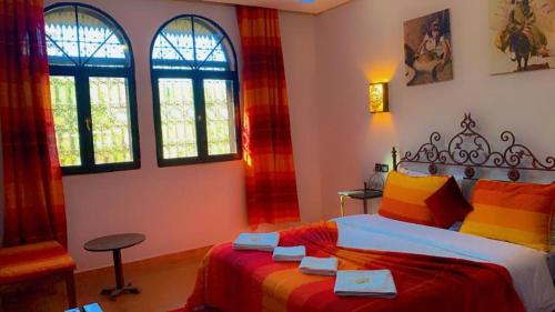 a bedroom with a bed with colorful sheets and windows at Les Jardins Yasmina Bin el-Ouidane in Bine el Ouidane