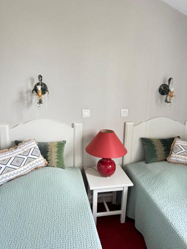 - une chambre avec 2 lits et une lampe rouge sur une table dans l'établissement Charmante Maison Duplex en résidence avec piscine à Monflanquin, à Monflanquin