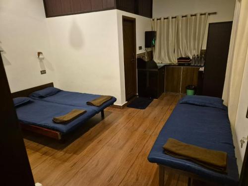 two beds in a room with wooden floors at Stanrose Farm Stay in Kundapur