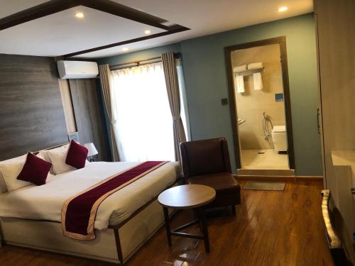 a hotel room with a bed and a chair and a bathroom at होटेल गोदावरी Lalitpur in Godāvari