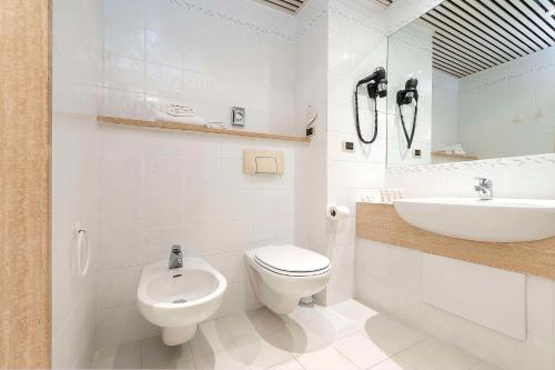 a white bathroom with a toilet and a sink at Best Western Hotel Quattrotorri in Perugia