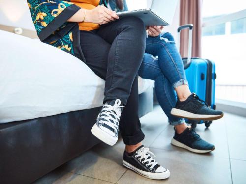 two people sitting on a bed with a laptop at ibis budget Singapore Imperial in Singapore