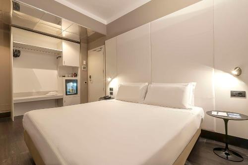 a white bedroom with a large bed and a table at Best Western Hotel Quattrotorri in Perugia