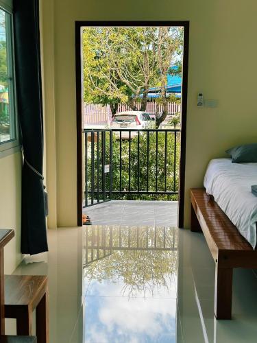 a bedroom with a door to a balcony with a bed at บ้านอยู่ดีโฮมสเตย์ in Ban Hua Khao