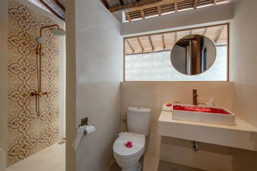 a bathroom with a toilet and a sink and a mirror at Sunset Joglo Pool Villa in Kerobokan