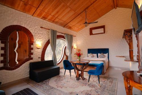 a bedroom with a bed and a table and chairs at Chirping Hills Resort,Bhimtal in Bhīm Tāl
