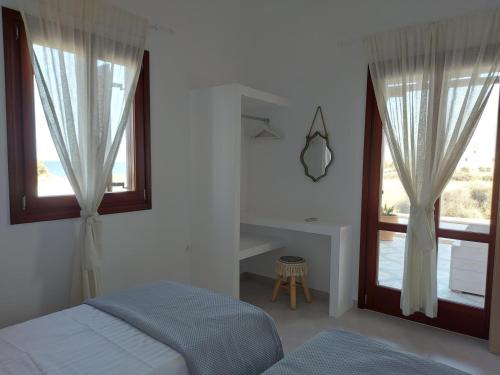a white bedroom with a bed and a window at Beach front Villa Pasithea in Monolithos