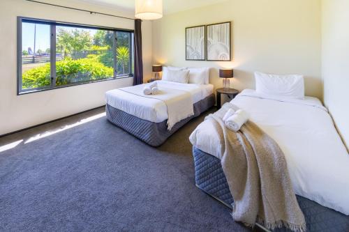 two beds in a room with a large window at Families and Groups, Chch Airport, Spa Pool in Christchurch