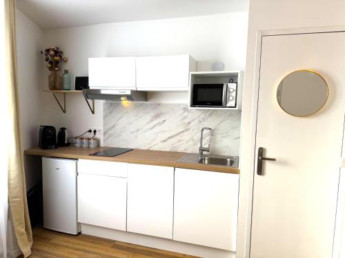 a white kitchen with a sink and a microwave at Résidence La Ruelle Secrete - 5 studios - in Ruelle-sur-Touvre