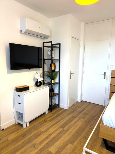 a bedroom with a white dresser and a tv on a wall at Résidence La Ruelle Secrete - 5 studios - in Ruelle-sur-Touvre