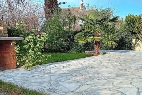 une allée pavée en face d'une maison avec un palmier dans l'établissement Maison individuelle 3 chambres, à Le Vaudreuil